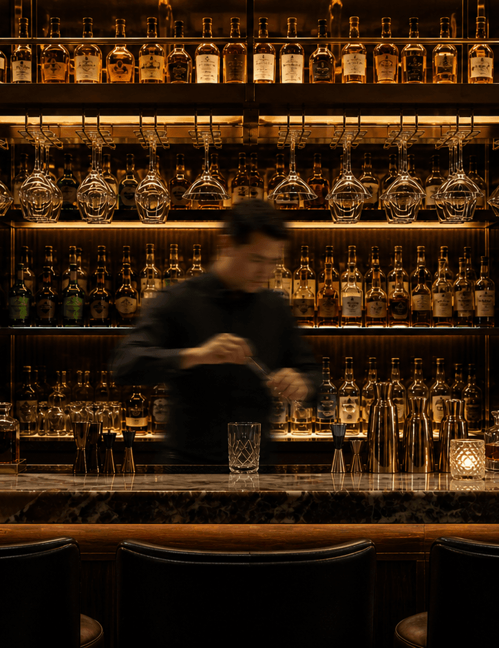 Bartender mixing drinks at a warmly lit cocktail bar
